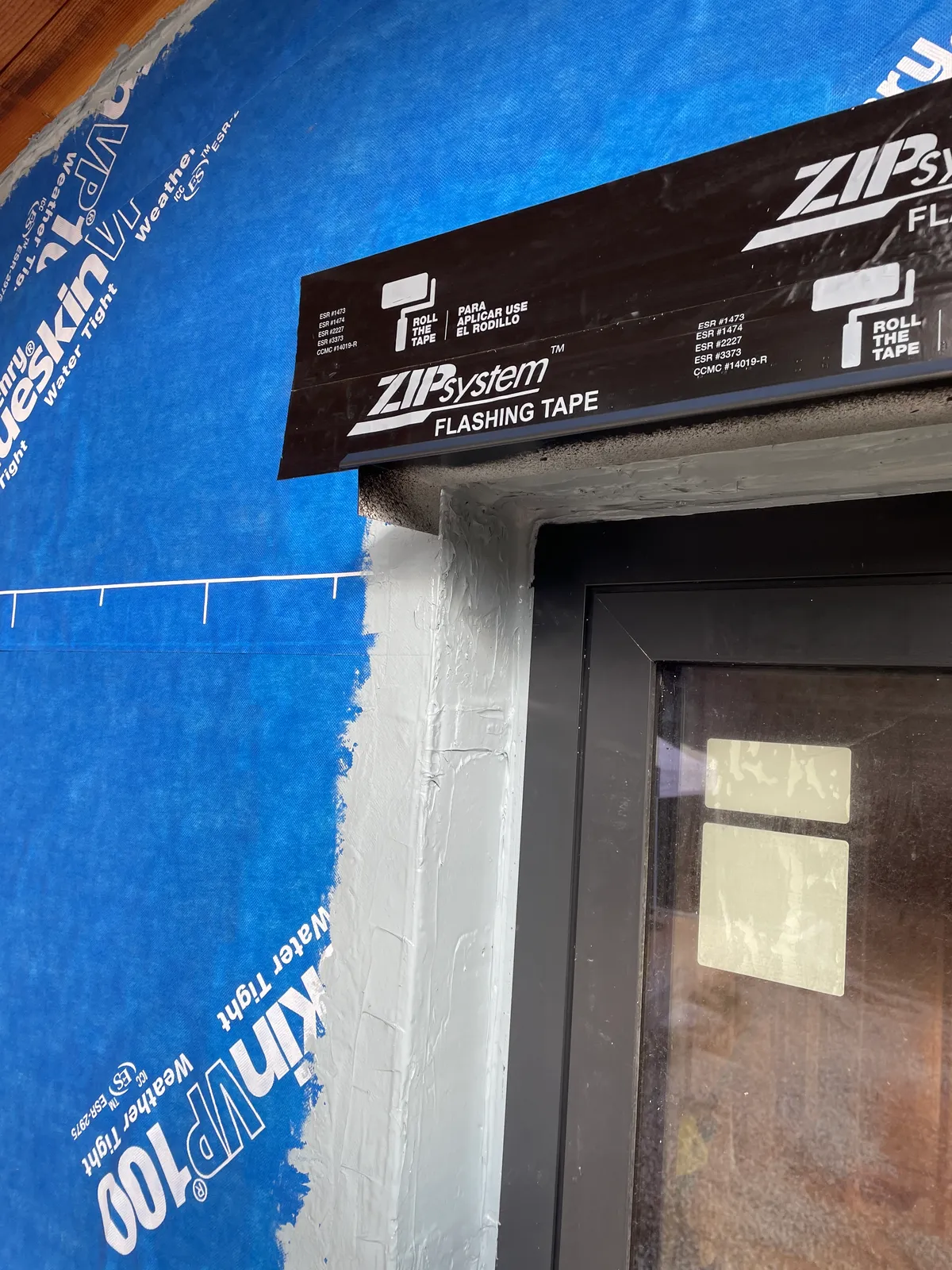 Window head flashing tape over a blue weather-resistive barrier