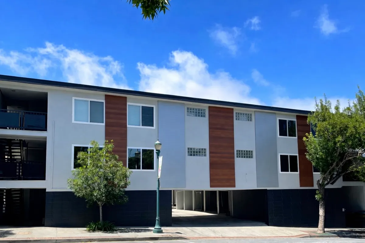 Three-story apartment building with wood-clad accent panels above a covered parking level