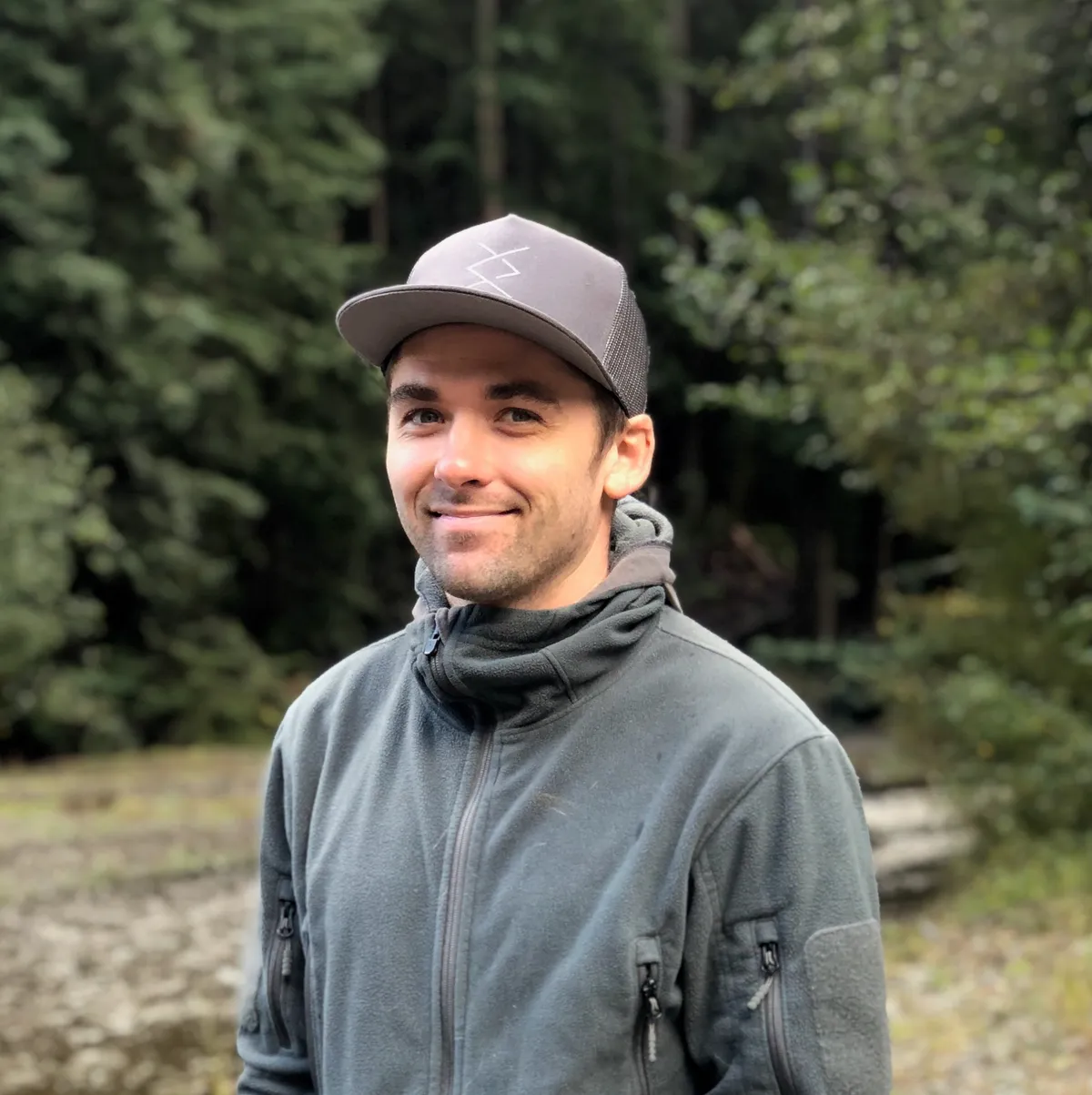 Matt Hart, portrait outdoors in front of evergreen trees